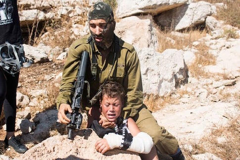 Israeli soldier holding Mohammed Tamimi, 12, in a headlock during West Bank protest