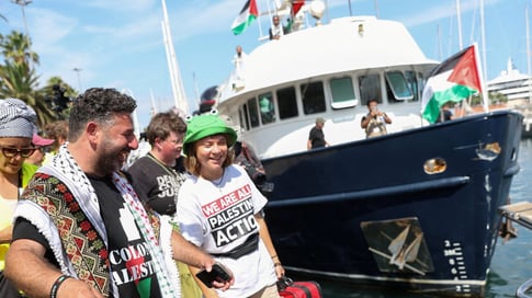 Sumud Flotilla activists on deck holding solidarity banners while defying Israeli threats