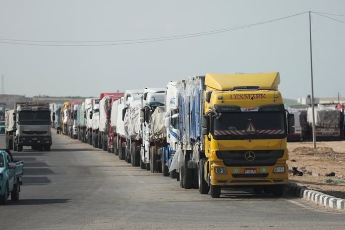 Rows of humanitarian aid trucks at Kerem Shalom crossing as inspections slow throughput.