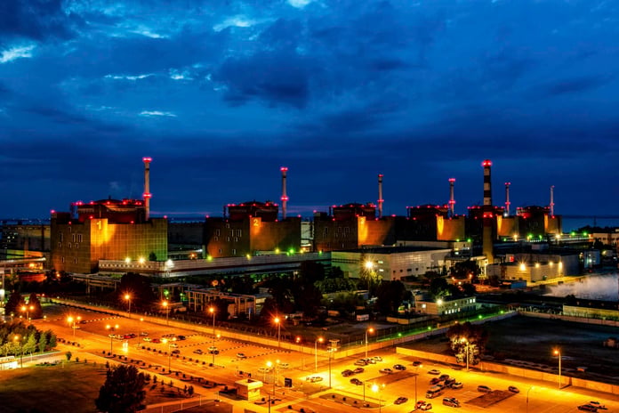 Zaporizhzhia nuclear power plant at dusk with cooling stacks and lights along the Dnieper