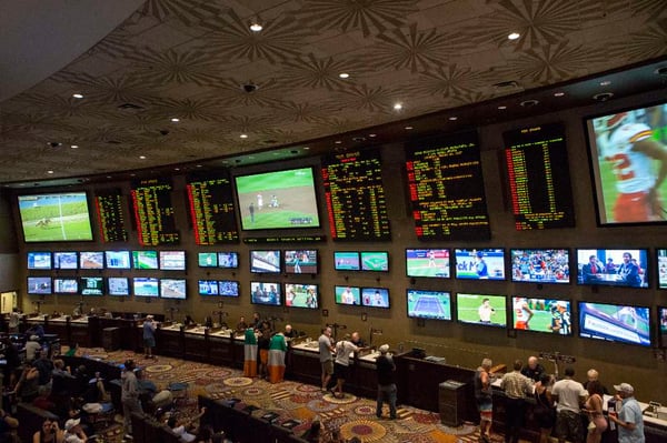 Kansas City sportsbook opening with patrons betting and large screens"