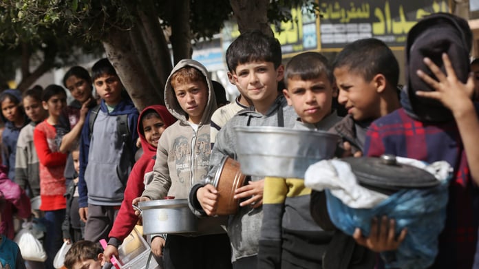 Palestinians including children queue for bread amid severe flour shortages in Gaza during ongoing war crisis