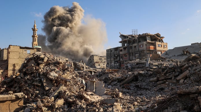 Palestinian civilians walk through destruction in Gaza after Israeli strikes