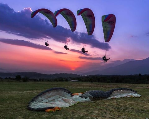 Paragliders flying over Bir Billing with Dhauladhar mountains in Himachal Pradesh