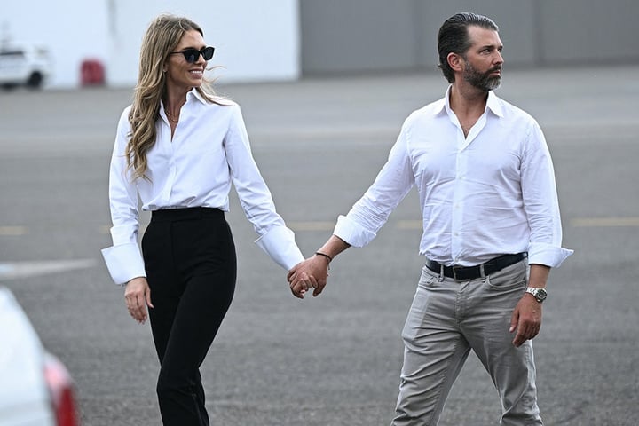 Donald Trump Jr. and his fiancee Bettina Anderson walk together on the tarmac at Teterboro Airport in late 2025