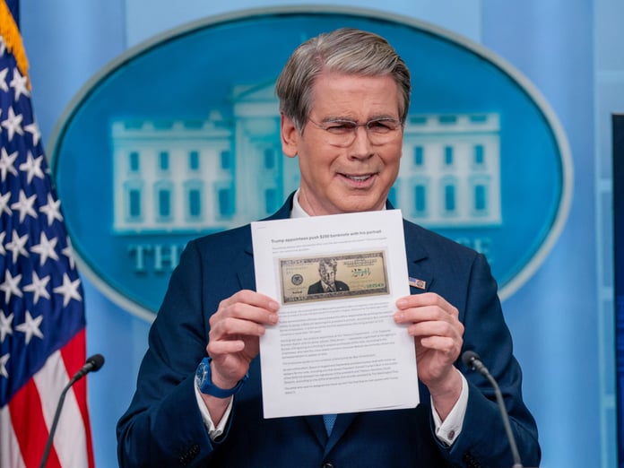 Treasury Secretary Scott Bessent holds up a Washington Post article about a proposed $250 bill featuring President Donald Trump at a White House briefing