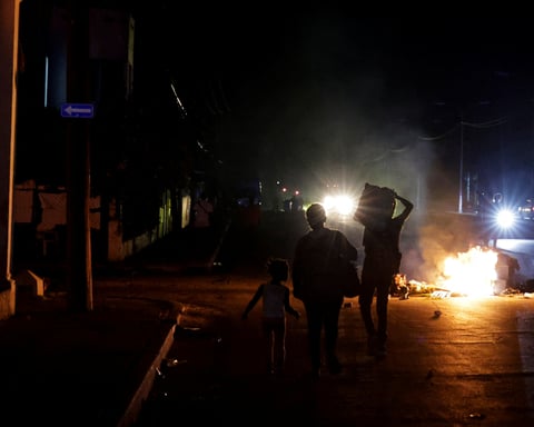 Residents walk past burning rubbish during protests over power cuts in Cuba