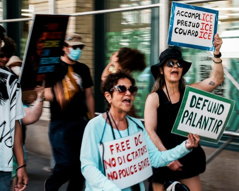 Protesters hold signs reading defund Palantir during a march outside Palantir's offices in New York