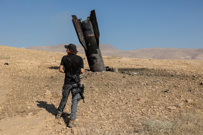 An Israeli settler inspects part of an Iranian missile protruding from the ground in the occupied West Bank June 8 2026