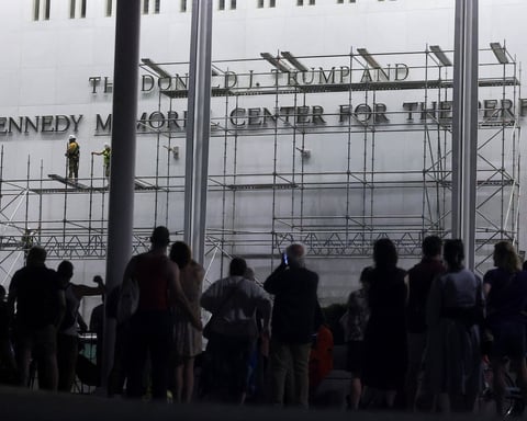 Workers on scaffolding remove lettering of Donald Trump's name from the Kennedy Center facade