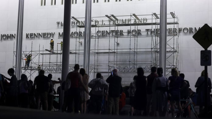 Workers on scaffolding remove lettering of Donald Trump's name from the Kennedy Center facade