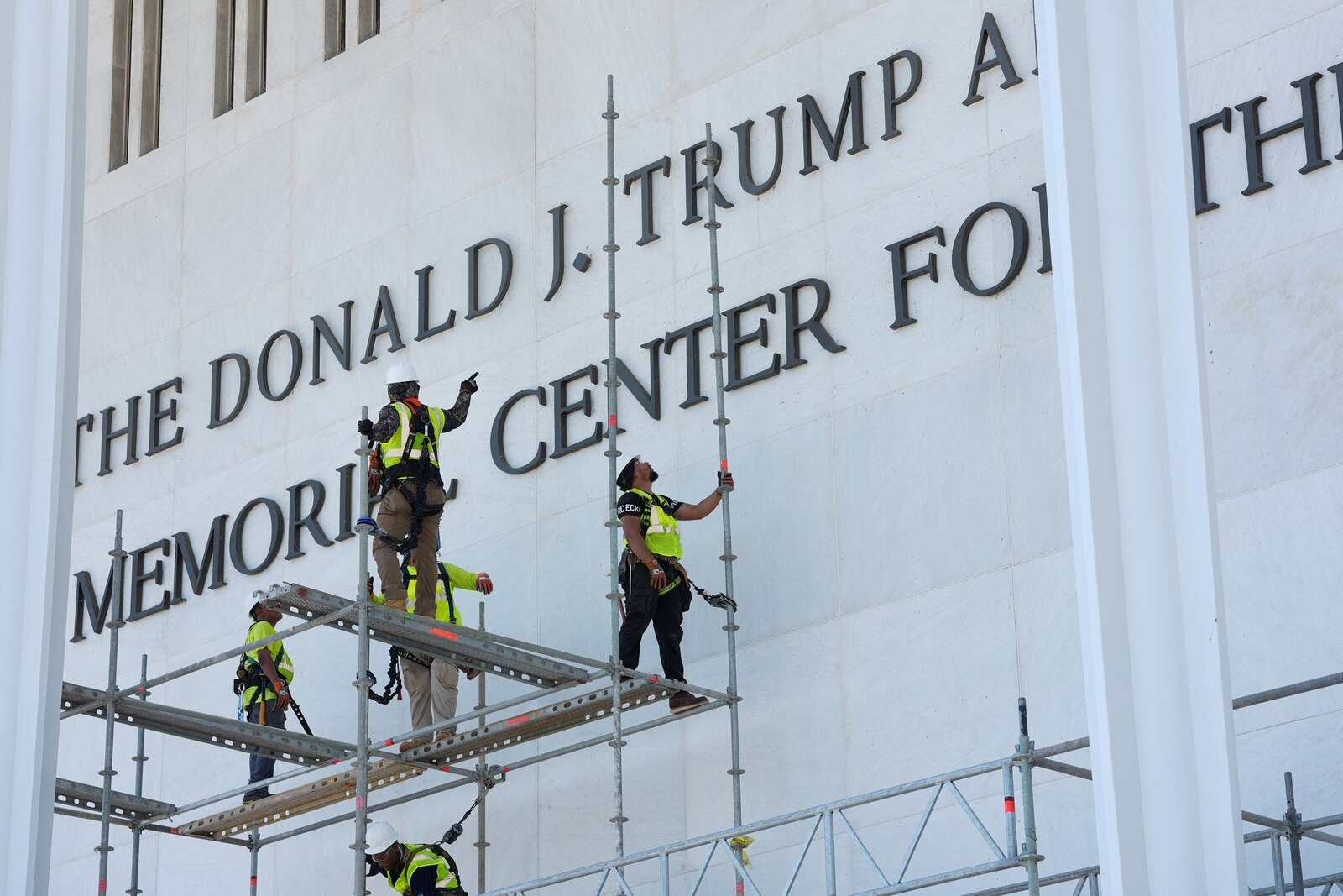 Workers remove the lettering of Donald Trump's name from the facade of the Kennedy Center