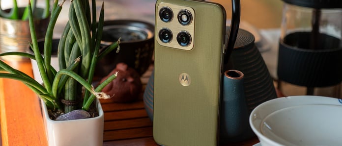 Motorola Edge 2026 in Pantone Martini Olive on a table next to a potted plant