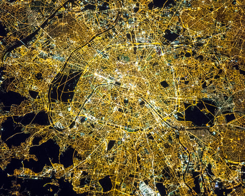 NASA astronaut photograph of Paris at night showing the Seine River as a thin black line with the bright Avenue des Champs Elysees and the radial street pattern around the Arc de Triomphe