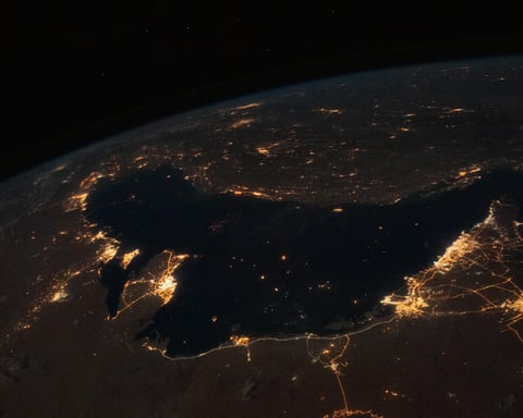 NASA astronaut photograph from the International Space Station of the Persian Gulf at night with the cities of Tehran, Dubai, Doha, Riyadh, Bahrain, and Kuwait City visible as bright clusters along the shoreline
