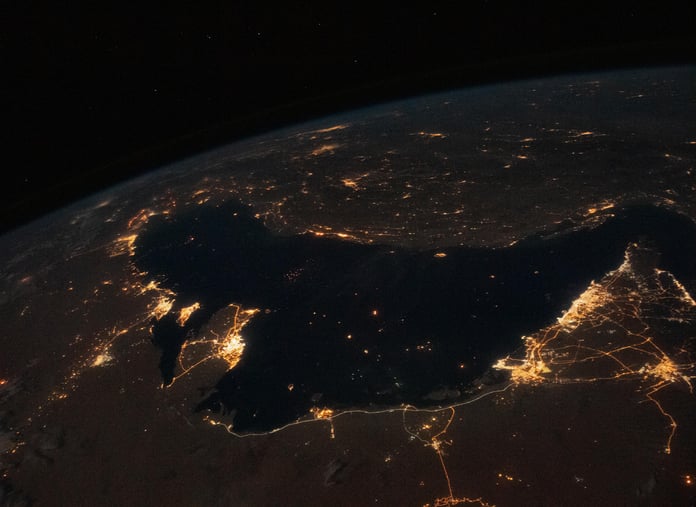 NASA astronaut photograph from the International Space Station of the Persian Gulf at night with the cities of Tehran, Dubai, Doha, Riyadh, Bahrain, and Kuwait City visible as bright clusters along the shoreline