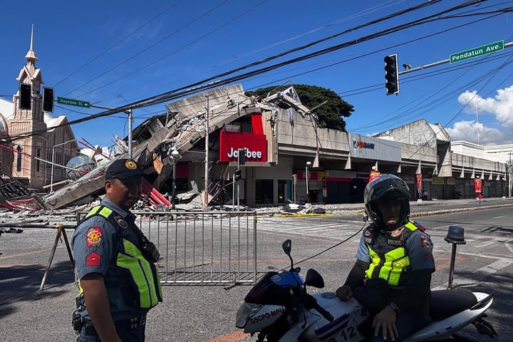 Police gather in front of a collapsed building after a magnitude 7.8 earthquake in General Santos, Philippines