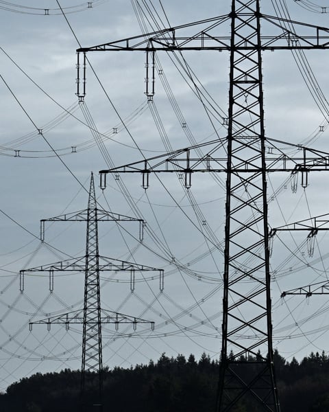 High-voltage power lines and electricity pylons near the A24 motorway in Germany, illustrating the COP31 electrification target