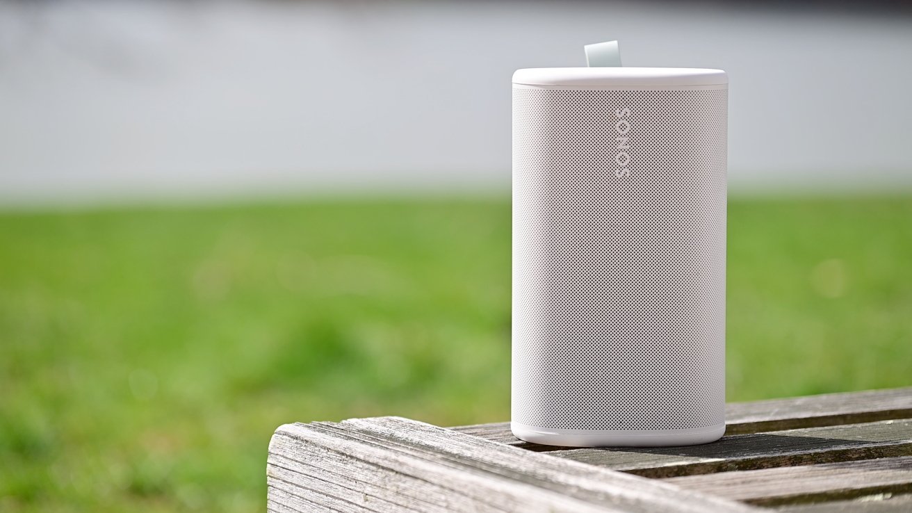 Sonos Play portable speaker held outdoors in bright sunlight, showing its cylindrical white design and compact size