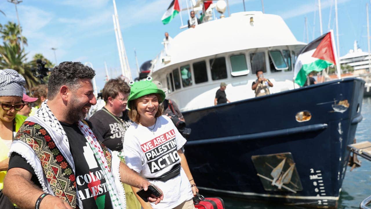 Sumud Flotilla activists on deck holding solidarity banners while defying Israeli threats