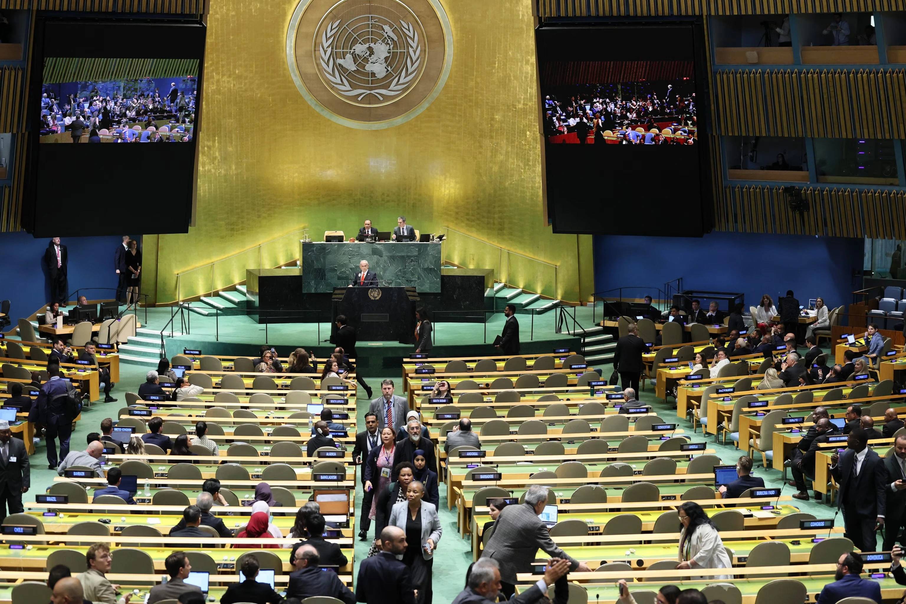 Benjamin Netanyahu at the UNGA rostrum as delegates exit, leaving rows of empty blue seats in New York.