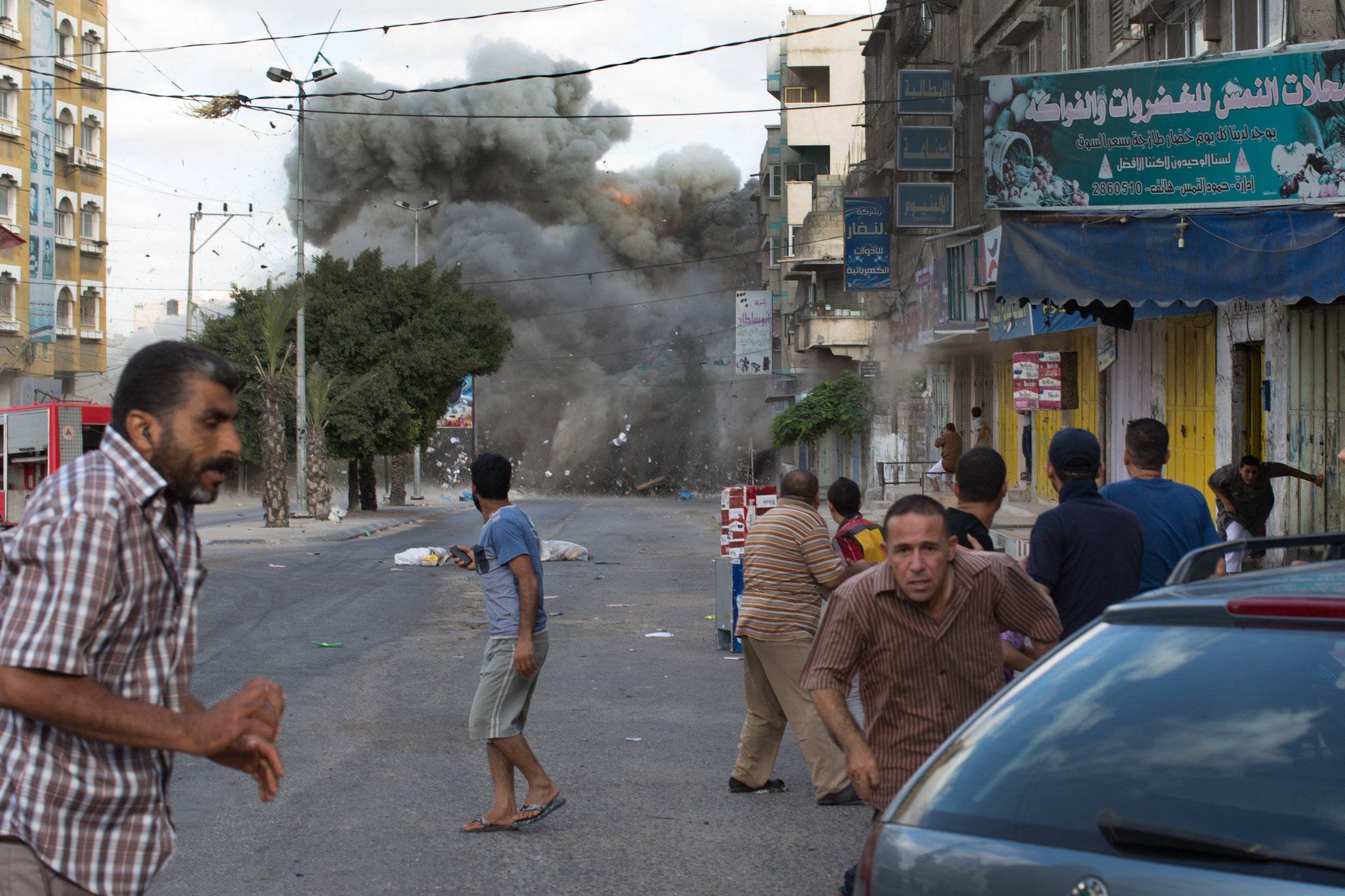 Families pick their way through a gutted Gaza City street