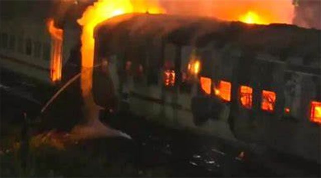 Burning train carriage on a railway track in Pakistan after a separatist bomb attack