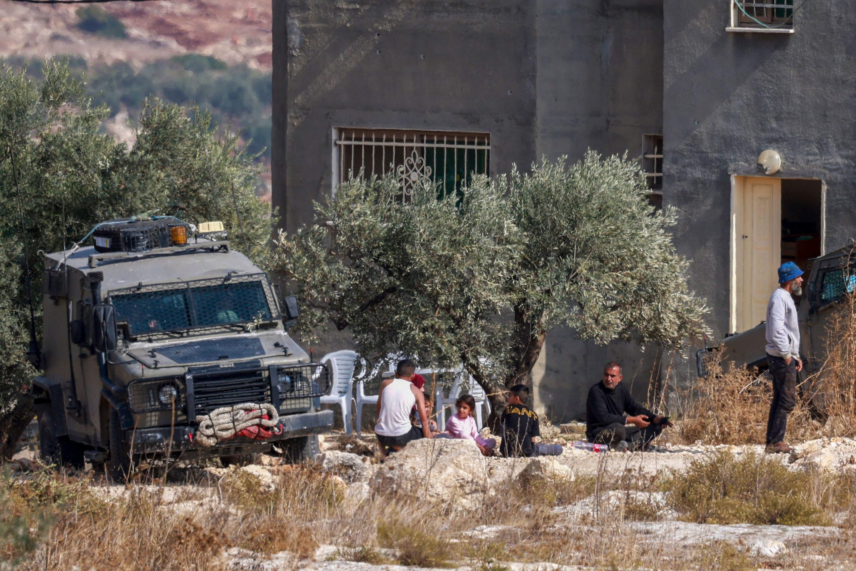 Israeli soldiers detain a family outside a house where a Palestinian