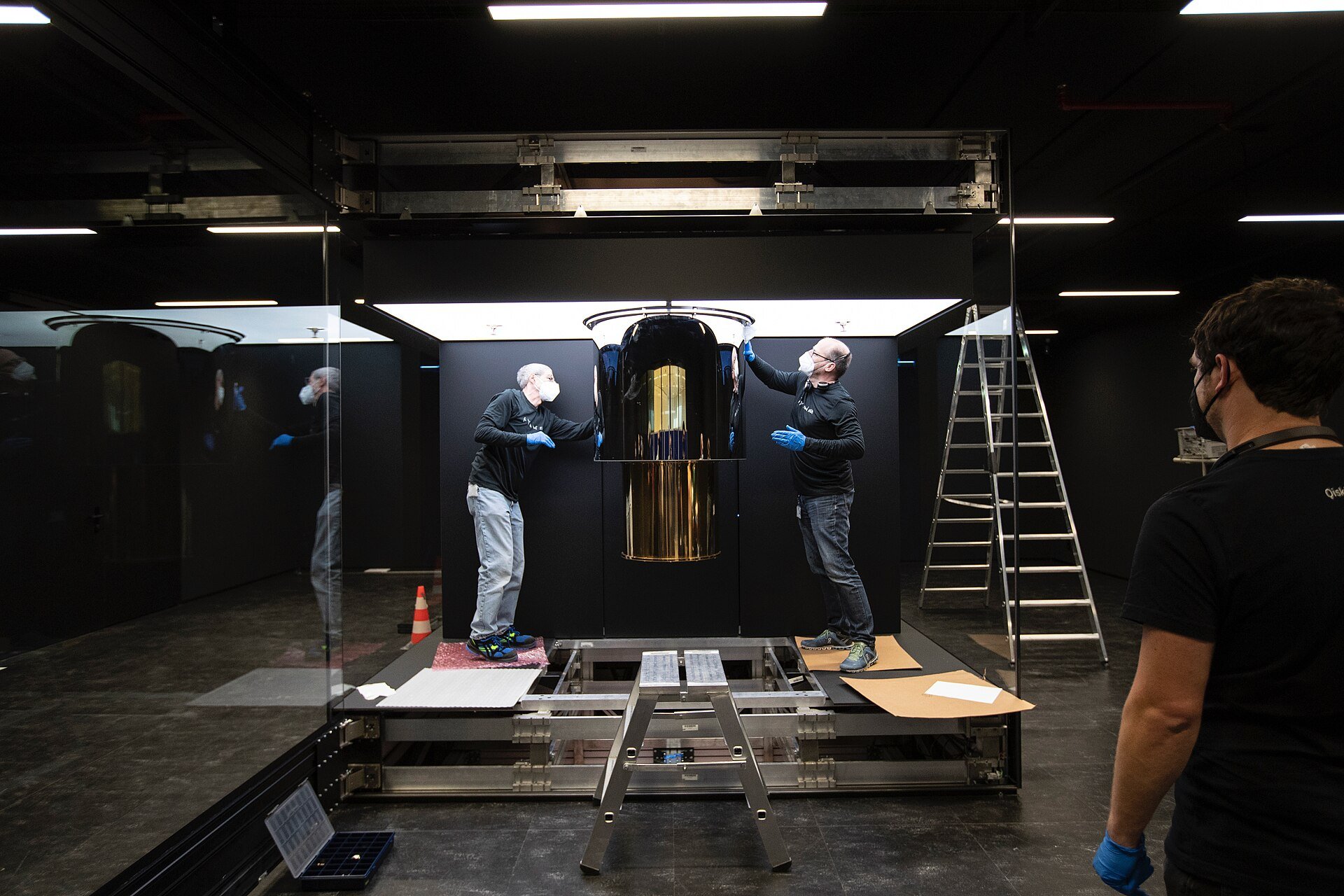 An IBM Q System One quantum computer, its gold-plated cabling suspended inside a sealed glass enclosure