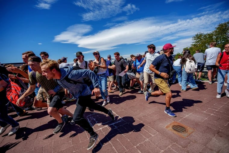 Police secure the Utah Valley University courtyard in Orem after the shooting of Charlie Kirk, with the Losee Center roofline visible in the background.