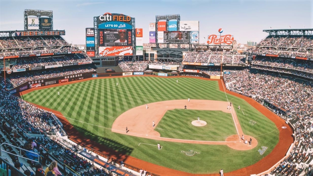 Aerial view of Citi Field and surrounding parking lots in Queens with Arthur Ashe Stadium in the background