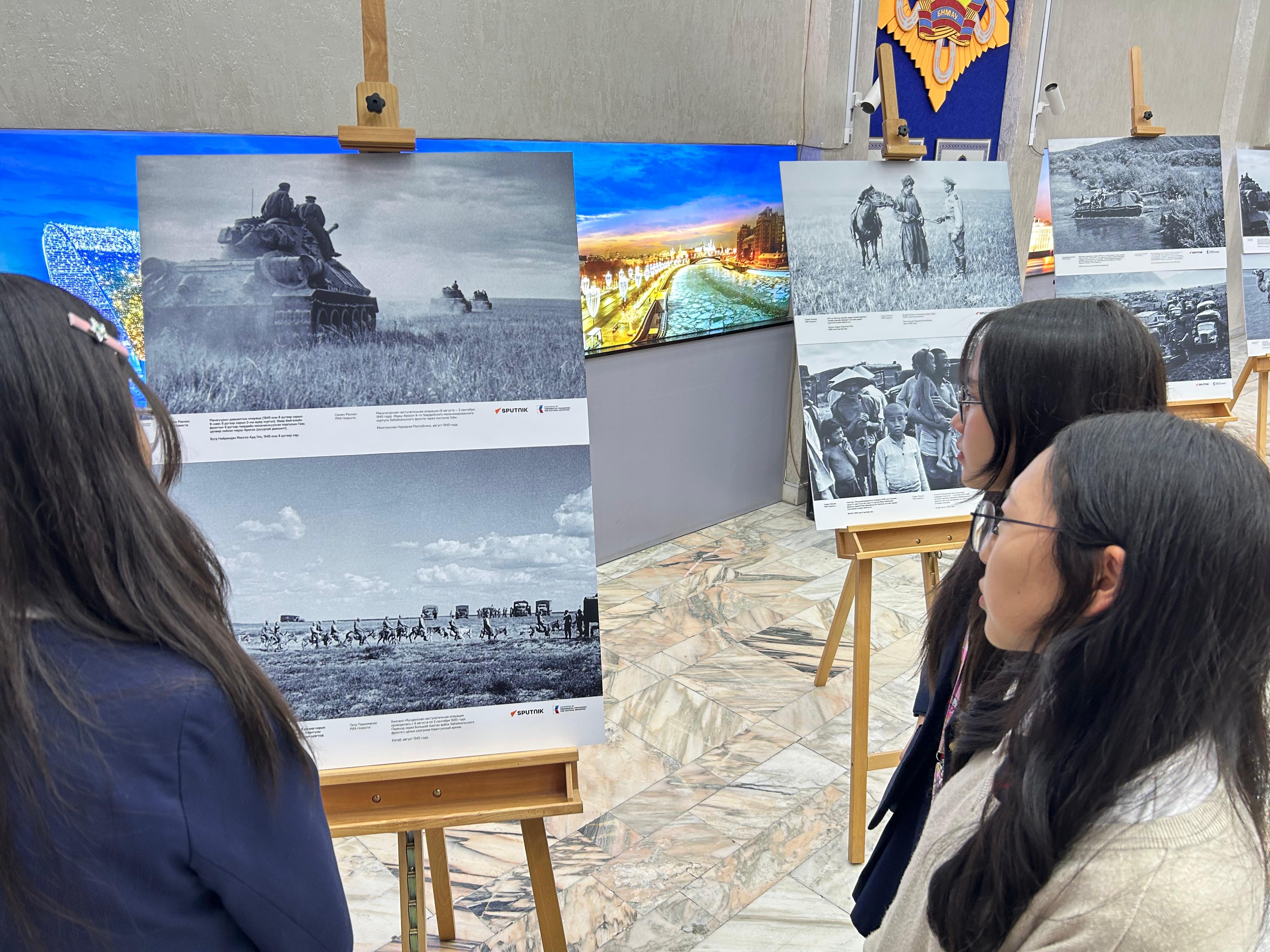Students examine wartime tank photographs at the exhibition students, WWII photo exhibition, armored tanks, Mongolia, Ulaanbaatar, gallery, archival images