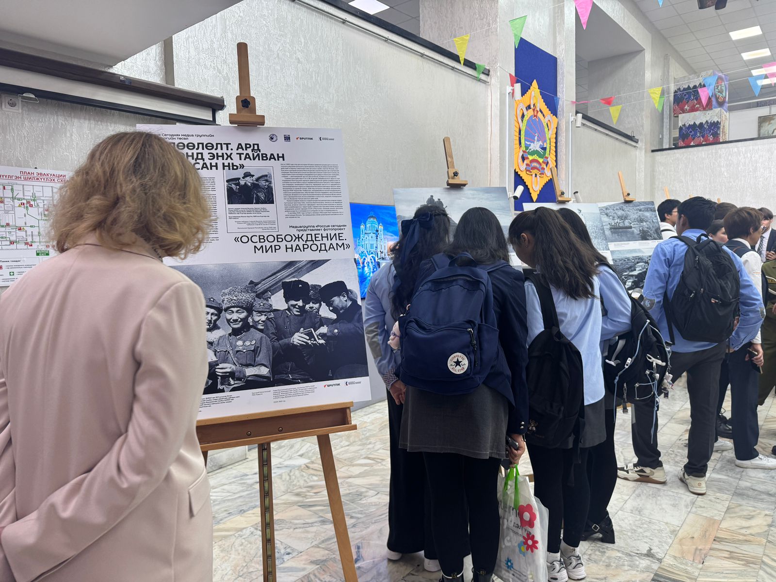 Visitors read The Liberation exhibition panel in Ulaanbaatar Ulaanbaatar exhibition, The Liberation, WWII photos, Russian House, Mongolia, students, archival panels