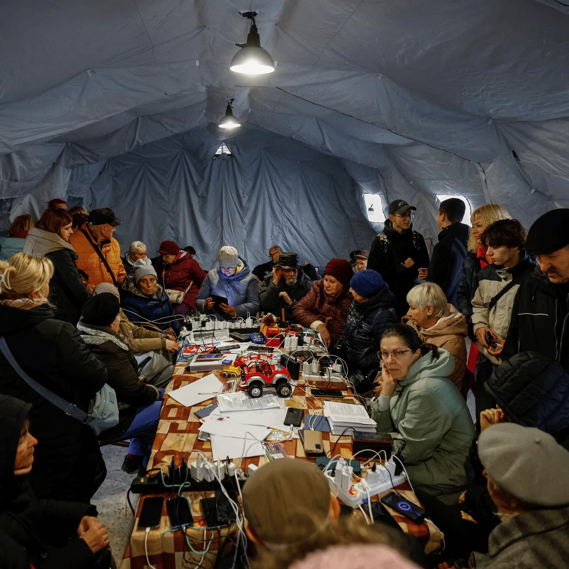 People charge phones and warm up at a public ‘Point of Invincibility’ in Chernihiv during power cuts.