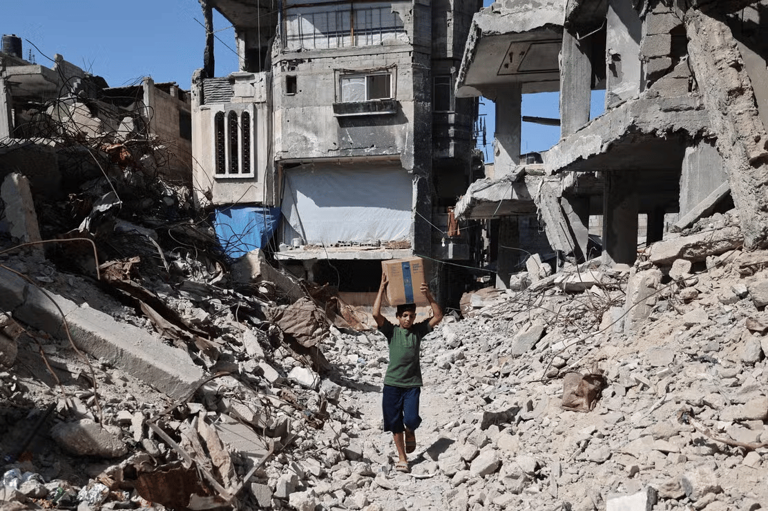 Displaced families gather at a damaged shelter in Nuseirat during the Gaza truce