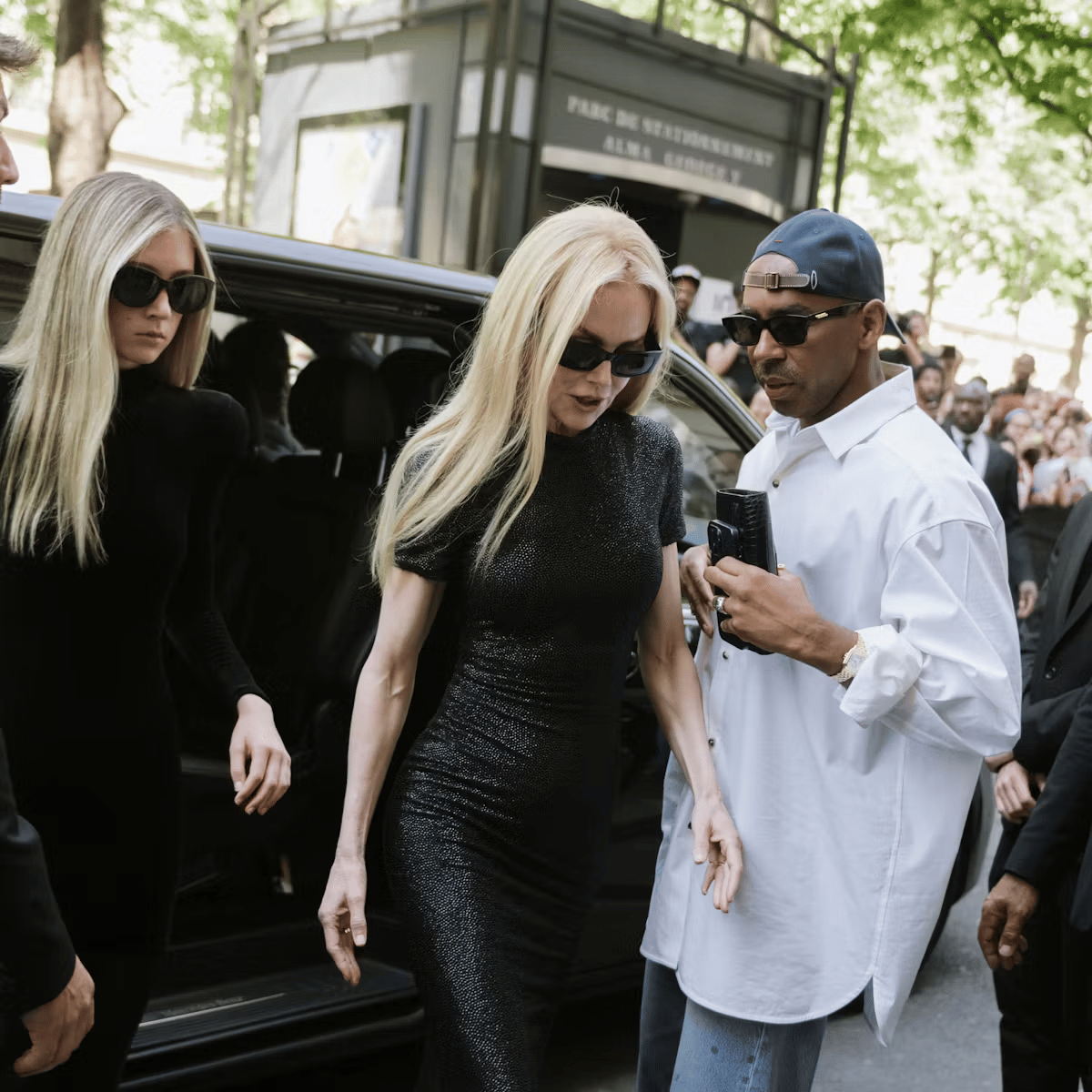 Nicole Kidman in a black dress holding an umbrella outside a Paris venue