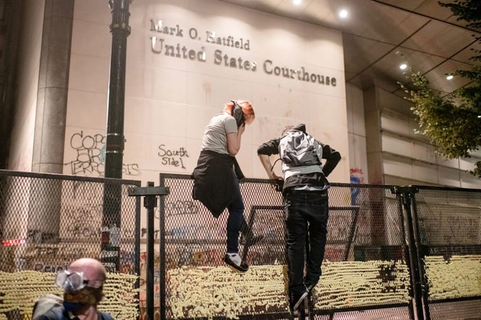 Protesters gather near fencing outside the federal courthouse in Portland