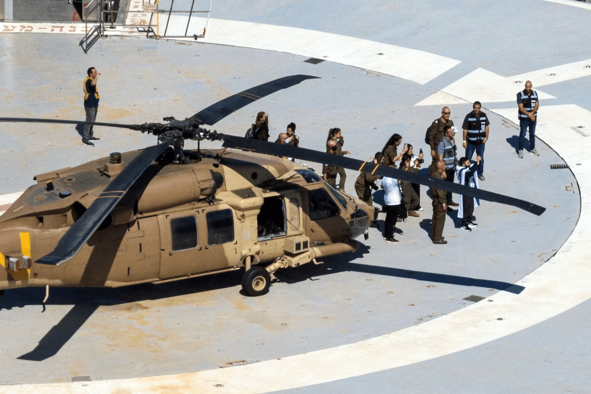 Israelis react as a helicopter carrying released hostages lifts off at Reim
