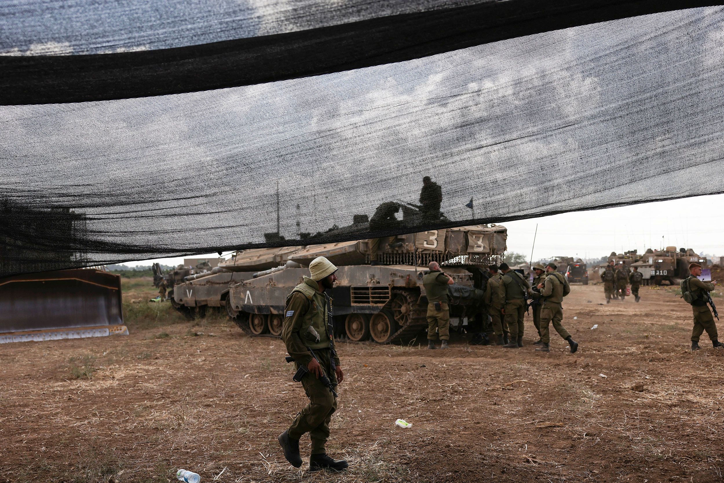Israeli soldiers at a roadside checkpoint near the Gaza perimeter with a directional sign to Gaza visible in the background