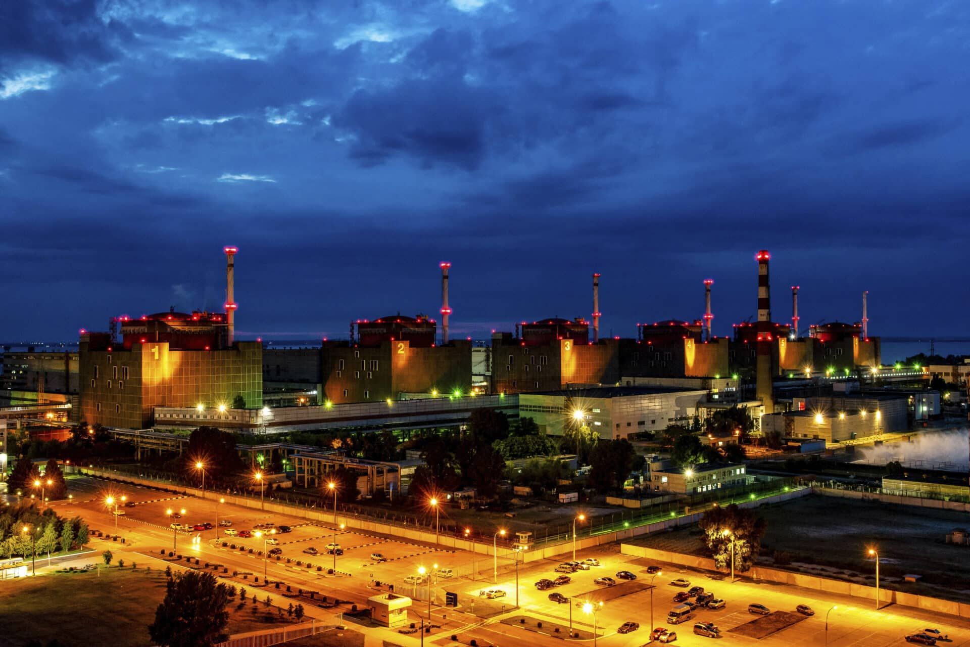 Zaporizhzhia nuclear power plant at dusk with cooling stacks and lights along the Dnieper