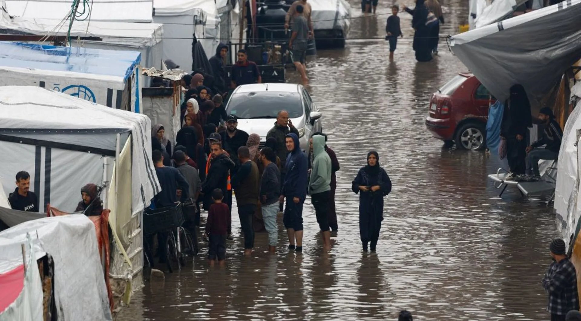 Palestinian children stand beside collapsed tents flooded by Storm Byron in Gaza displacement camp December 2025