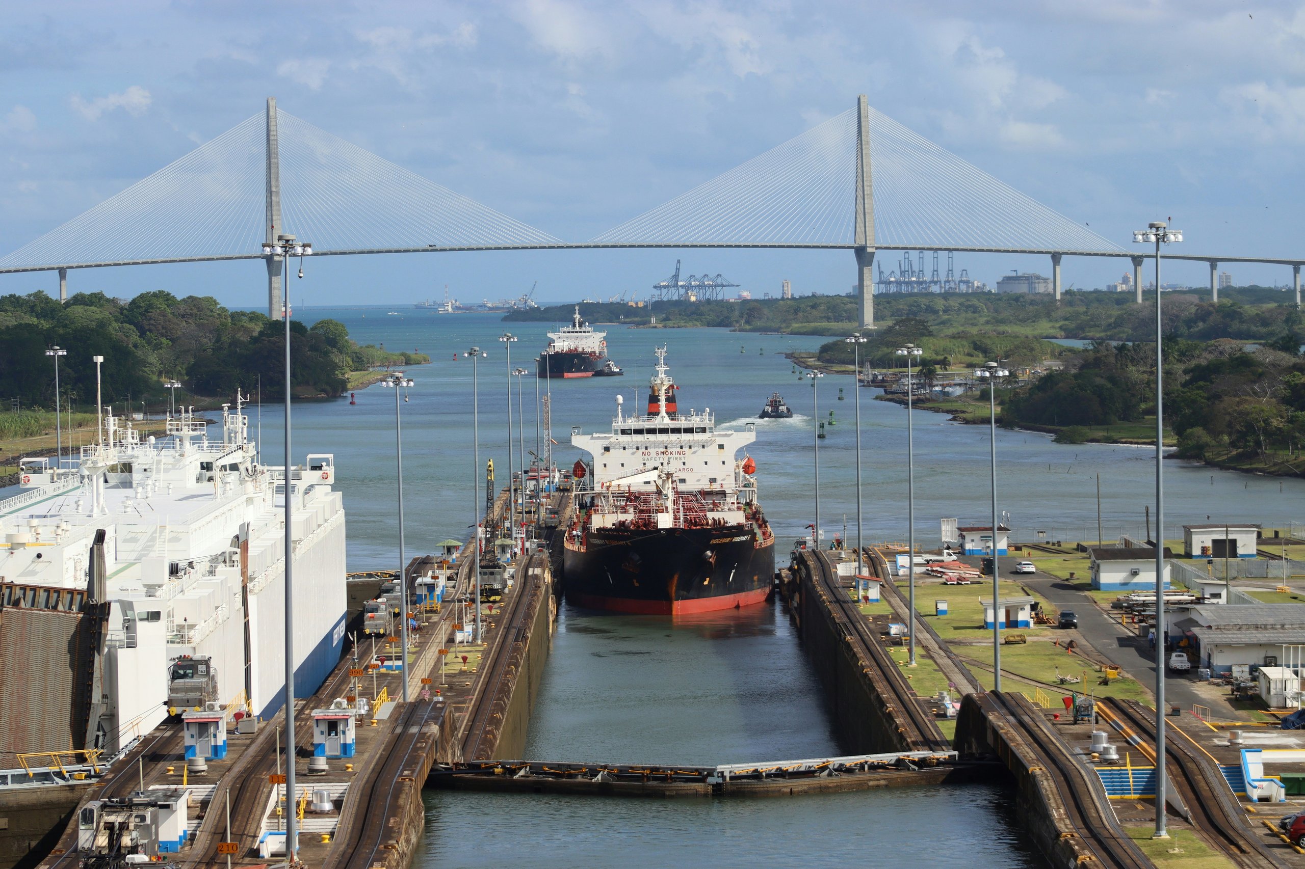 Ships transiting through Panama Canal Gatun Locks with rainforest watershed in background