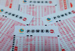 Powerball lottery ticket with $1.7 billion jackpot displayed alongside cash money for Christmas Eve 2024 drawing