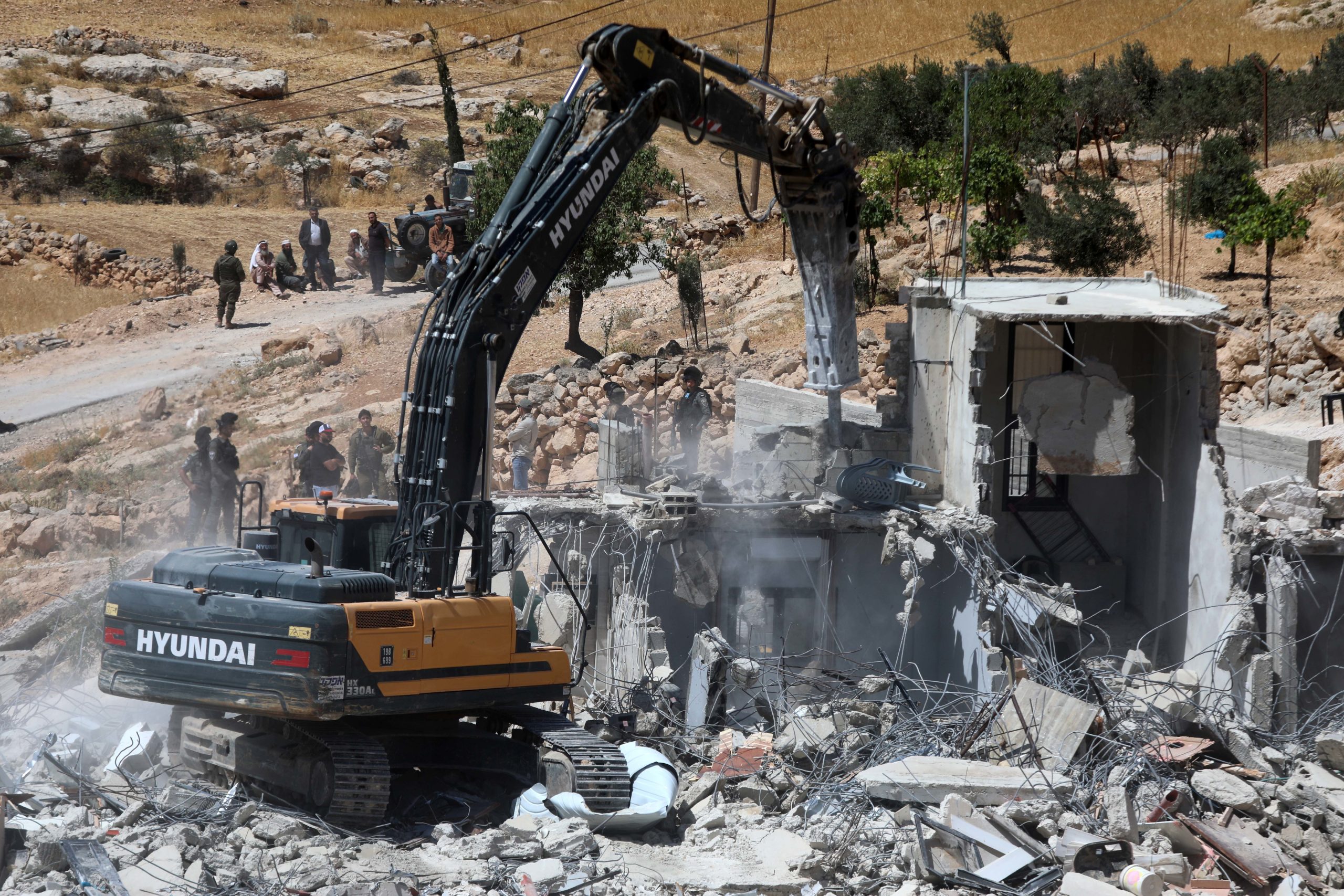 Israeli settlers bulldozing Palestinian homes in the occupied West Bank.