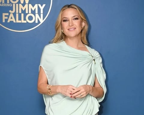 Kate Hudson wearing a mint green one-shoulder Sportmax dress with a thigh-high slit on The Tonight Show Starring Jimmy Fallon in 2026.