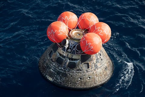 Orion spacecraft floating in the Pacific Ocean after Artemis II lunar mission splashdown with NASA recovery teams nearby