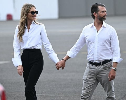 Donald Trump Jr. and his fiancee Bettina Anderson walk together on the tarmac at Teterboro Airport in late 2025
