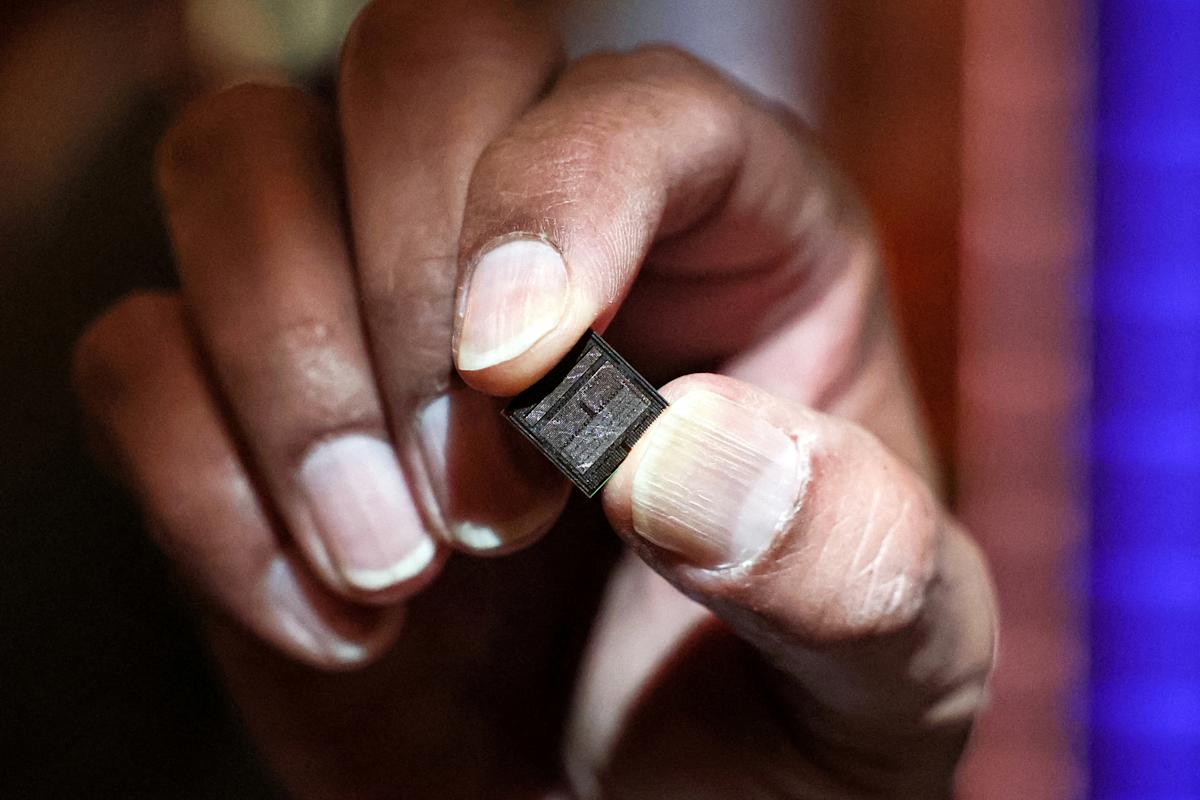 Micron Technology CEO Sanjay Mehrotra holds a high-bandwidth memory chip on the floor of the New York Stock Exchange