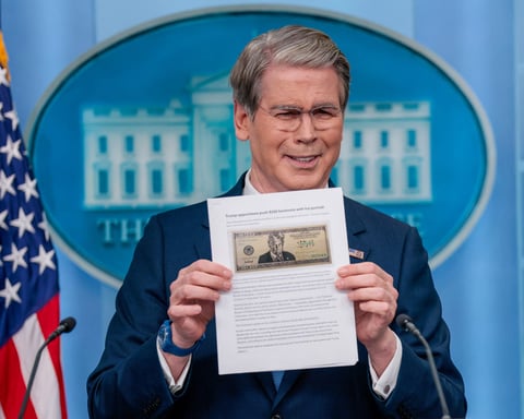 Treasury Secretary Scott Bessent holds up a Washington Post article about a proposed $250 bill featuring President Donald Trump at a White House briefing