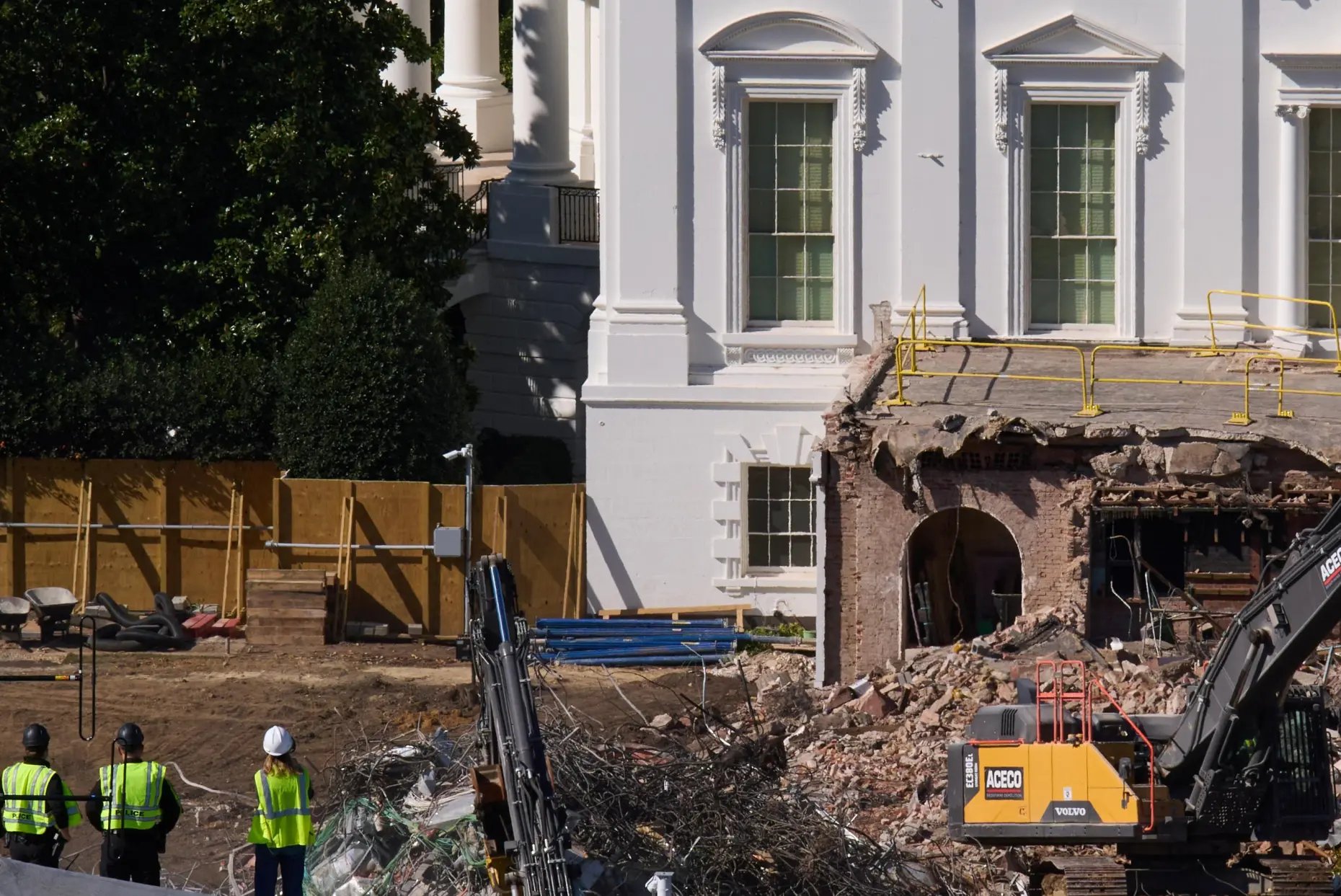 Construction workers on top of the U.S. Treasury watch demolition of the East Wing of the White House on October 23, 2025